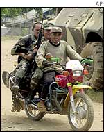 Filipino soldiers ride on motorcycle as they patrol at Isabela town, Basilan island, southern Philippines, 13 March 2002